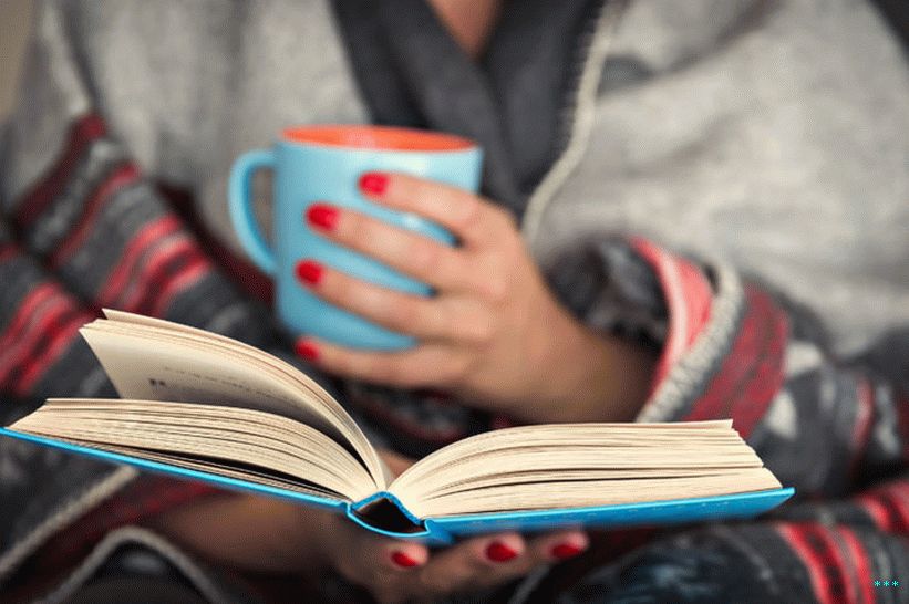 Fotografska fotografija odete ženske v odejo, ki bere knjigo.